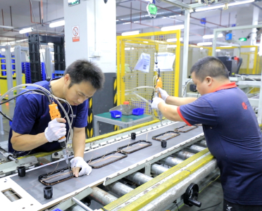 two factory workers working side by side on an assembly line